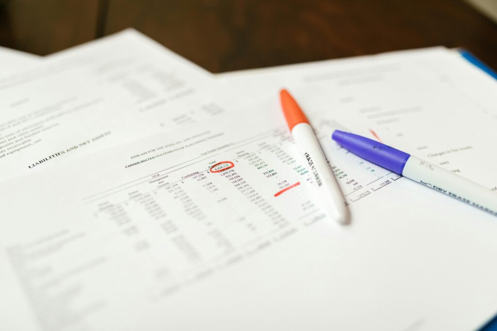 Close-up of financial documents with pens highlighting important data points.
